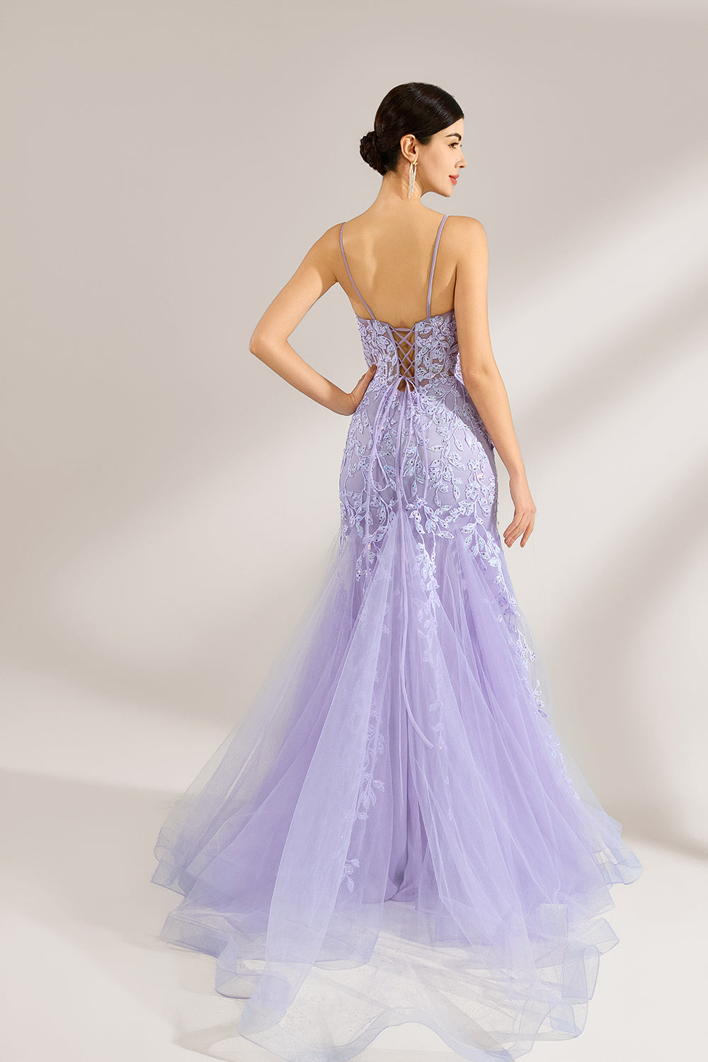 The model sports neatly arranged hair and dangles elegant long earrings. The gown is lavender, featuring a deep V - neckline and slender spaghetti straps. Intricate floral lace embellishes it, and the mermaid - cut skirt, crafted from airy tulle, exudes an elegant and dreamy charm, ideal for formal events.2