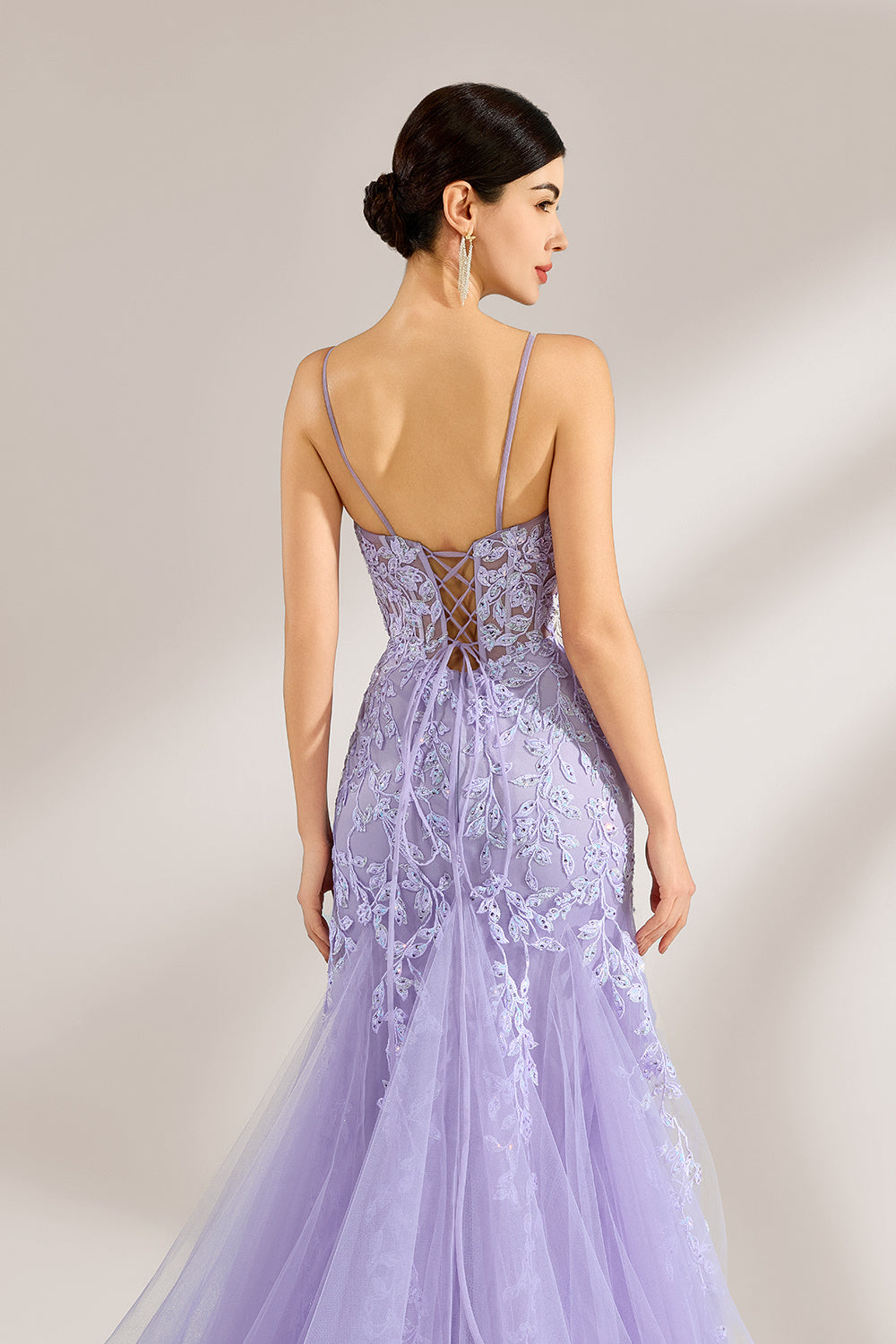 The model sports neatly arranged hair and dangles elegant long earrings. The gown is lavender, featuring a deep V - neckline and slender spaghetti straps. Intricate floral lace embellishes it, and the mermaid - cut skirt, crafted from airy tulle, exudes an elegant and dreamy charm, ideal for formal events.6