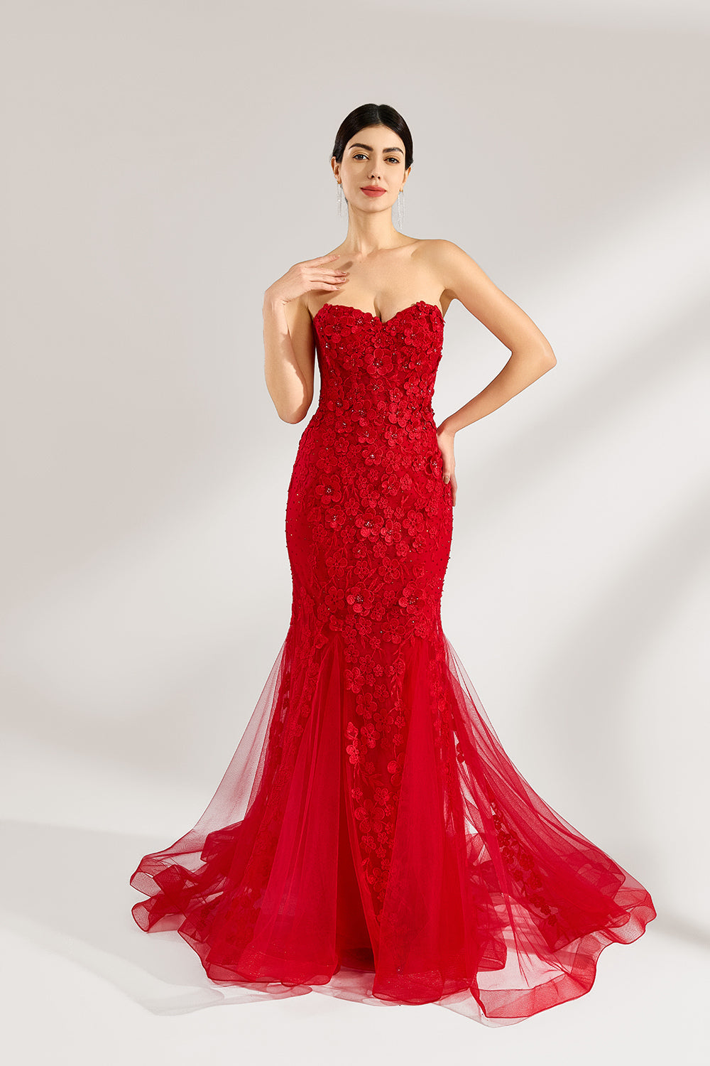 A woman stands against a light background, wearing a red mermaid - style gown. It features a strapless sweetheart neckline, intricate floral lace embroidery throughout, and a flowing tulle skirt with a train. The elegant design creates a glamorous and romantic look, perfect for formal events like proms or weddings.1
