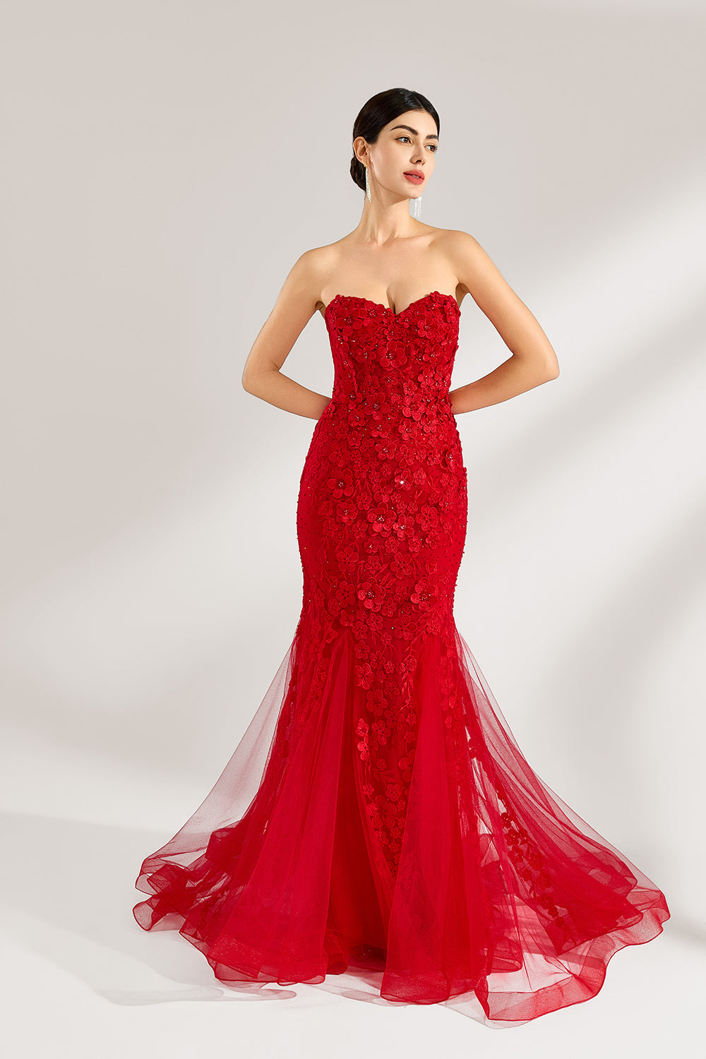 A woman stands against a light background, wearing a red mermaid - style gown. It features a strapless sweetheart neckline, intricate floral lace embroidery throughout, and a flowing tulle skirt with a train. The elegant design creates a glamorous and romantic look, perfect for formal events like proms or weddings.2