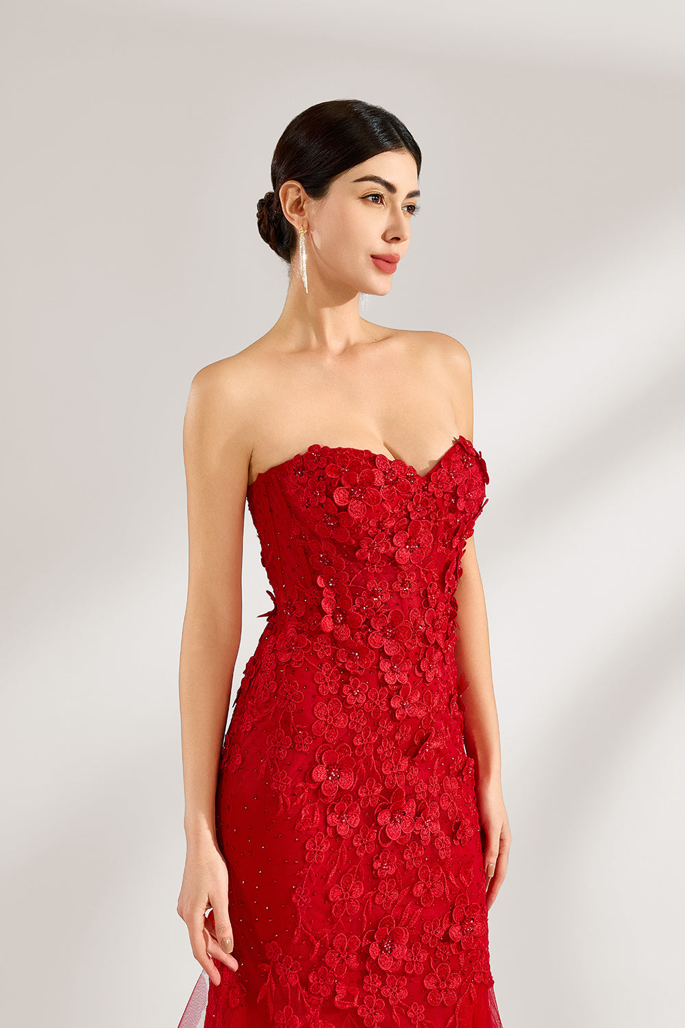 A woman stands against a light background, wearing a red mermaid - style gown. It features a strapless sweetheart neckline, intricate floral lace embroidery throughout, and a flowing tulle skirt with a train. The elegant design creates a glamorous and romantic look, perfect for formal events like proms or weddings.5