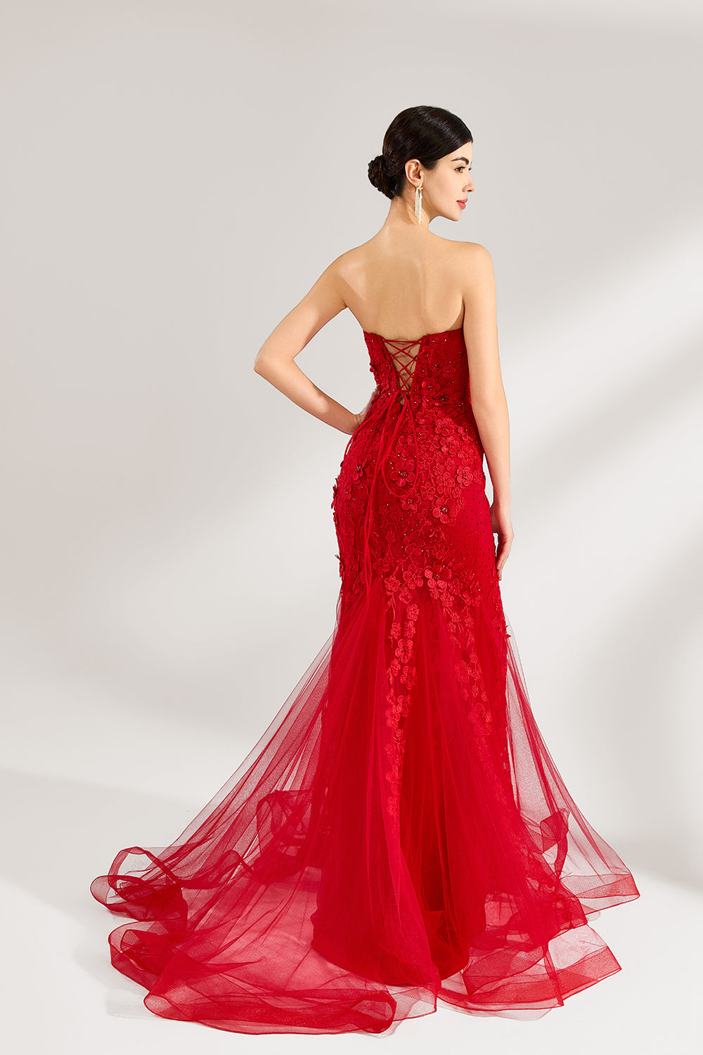 A woman stands against a light background, wearing a red mermaid - style gown. It features a strapless sweetheart neckline, intricate floral lace embroidery throughout, and a flowing tulle skirt with a train. The elegant design creates a glamorous and romantic look, perfect for formal events like proms or weddings.5