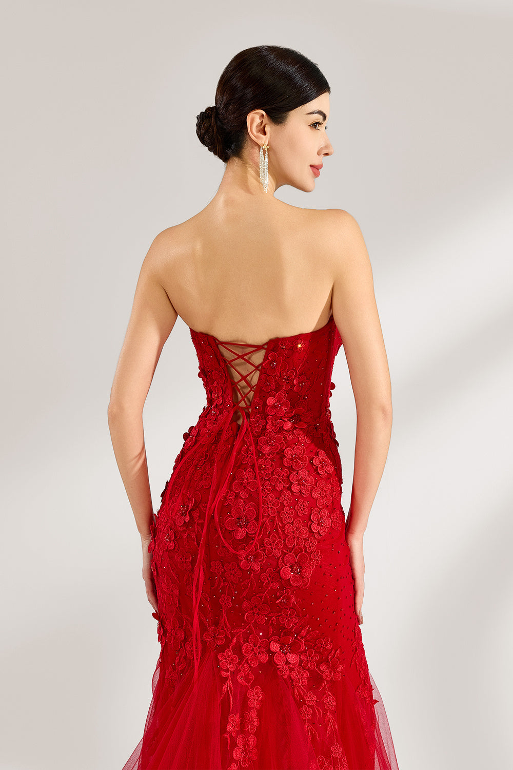 A woman stands against a light background, wearing a red mermaid - style gown. It features a strapless sweetheart neckline, intricate floral lace embroidery throughout, and a flowing tulle skirt with a train. The elegant design creates a glamorous and romantic look, perfect for formal events like proms or weddings.6