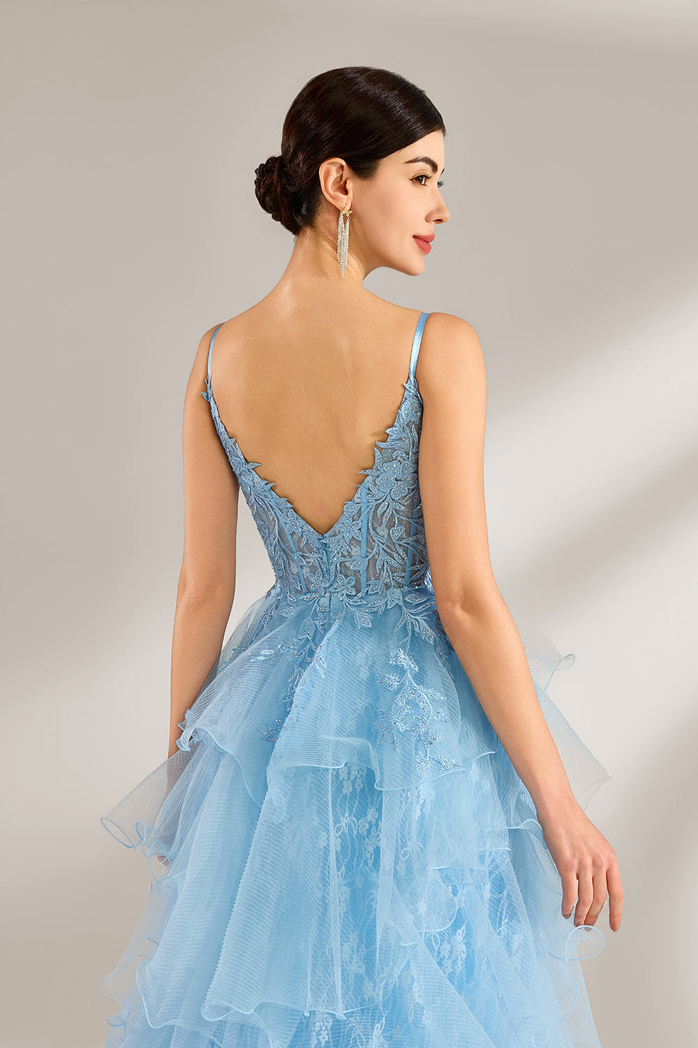 A woman stands against a light background, wearing a light - blue tulle gown. It has thin straps, a deep V - neckline, and intricate lace embroidery on the bodice. The layered, ruffled skirt with a high side slit creates a romantic and glamorous look, perfect for formal events like proms or weddings, exuding elegance and charm.5