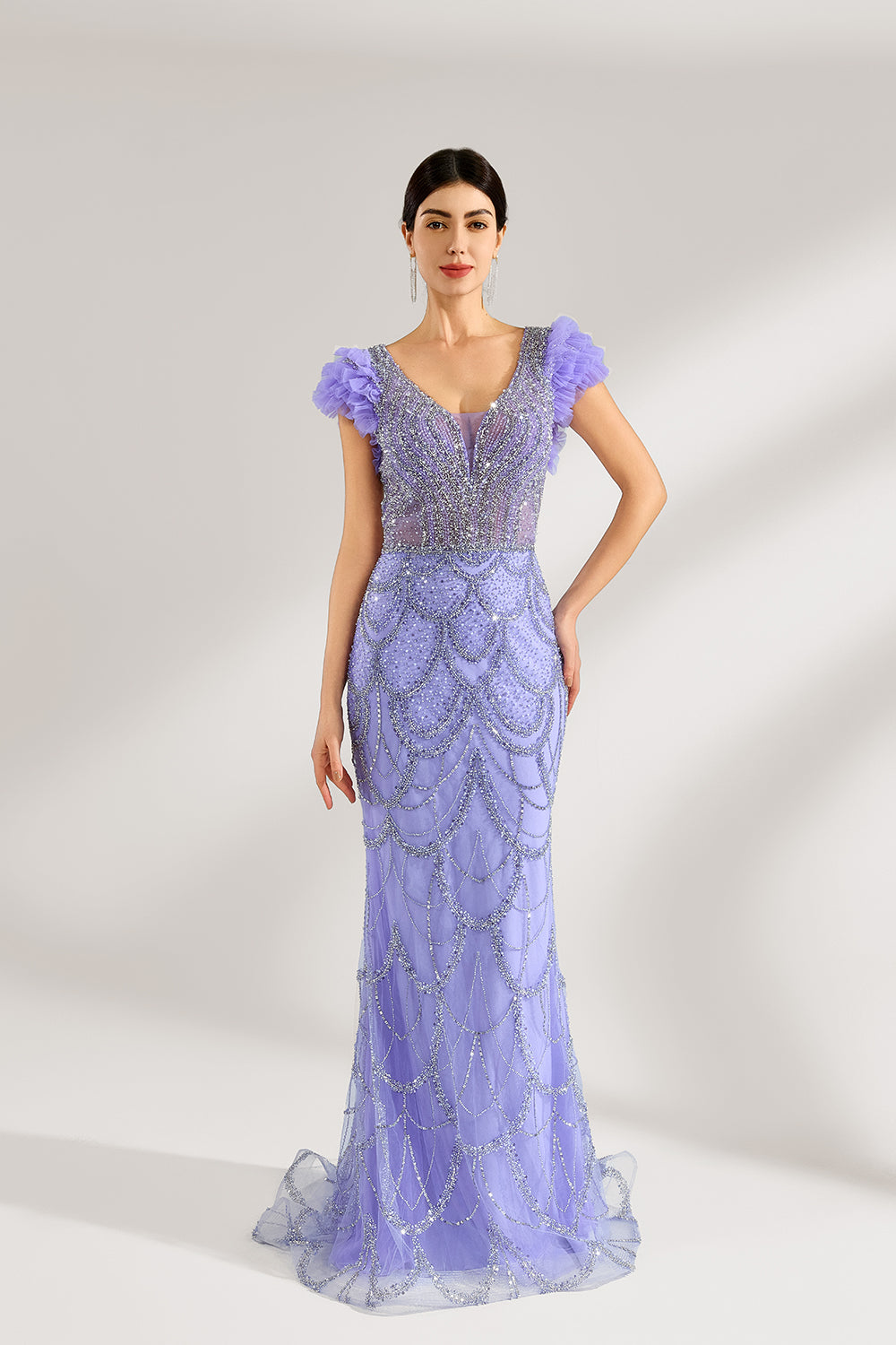 In soft lighting, a woman shines in a purple mermaid evening gown. It has sequin detailing, a V - neckline, and fluffy short sleeves, creating an elegant and glamorous look for formal events.1