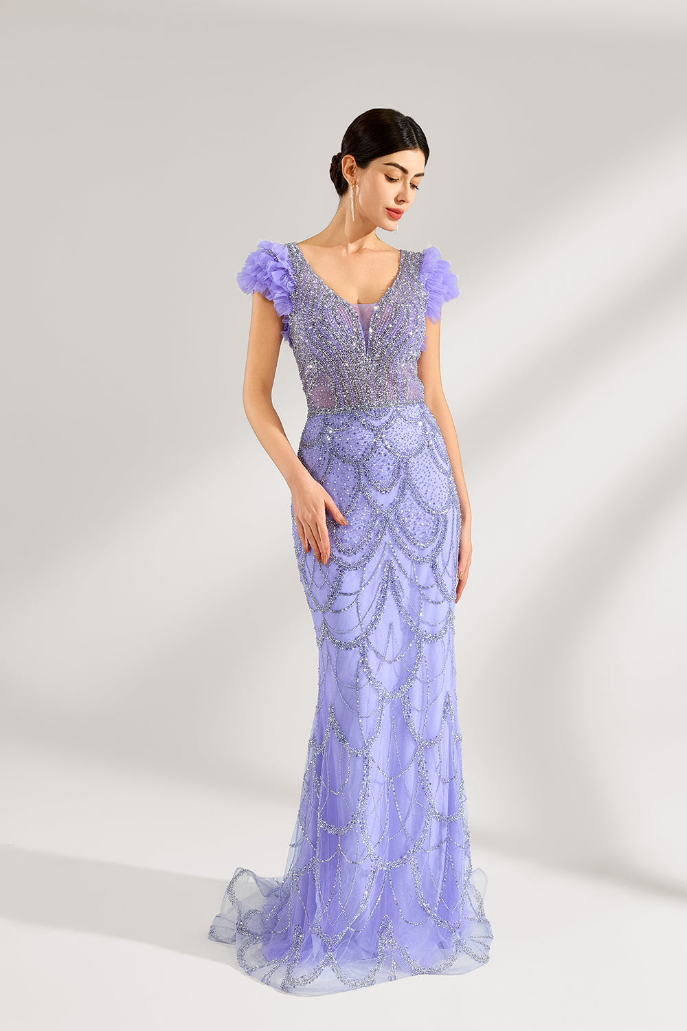 In soft lighting, a woman shines in a purple mermaid evening gown. It has sequin detailing, a V - neckline, and fluffy short sleeves, creating an elegant and glamorous look for formal events.3