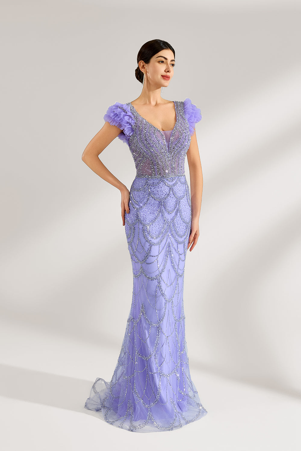 In soft lighting, a woman shines in a purple mermaid evening gown. It has sequin detailing, a V - neckline, and fluffy short sleeves, creating an elegant and glamorous look for formal events.4