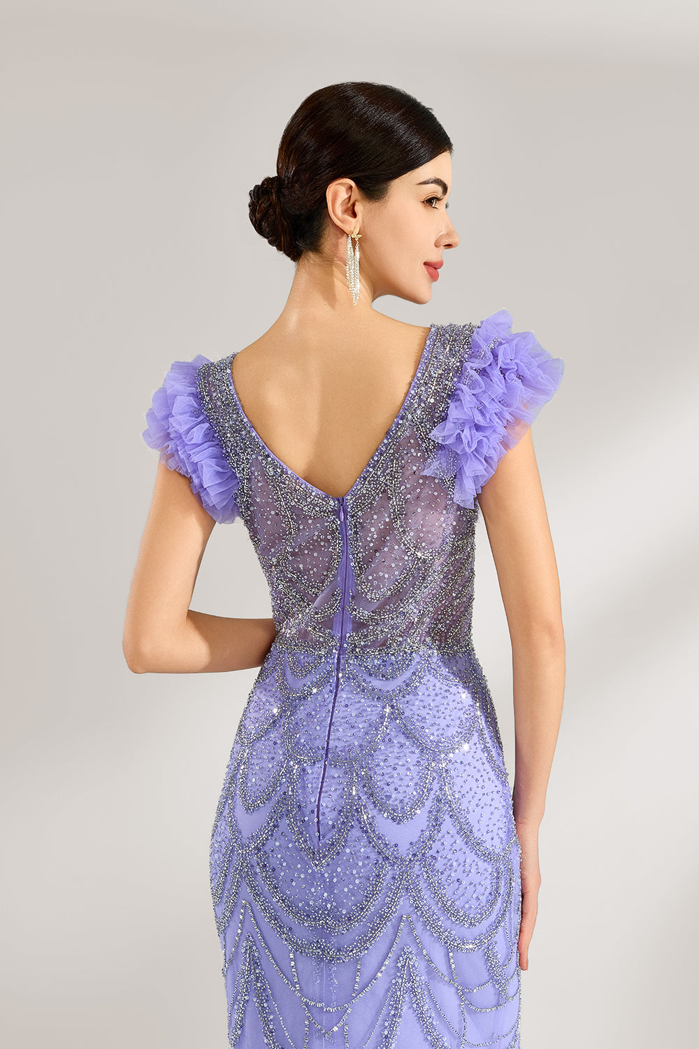 In soft lighting, a woman shines in a purple mermaid evening gown. It has sequin detailing, a V - neckline, and fluffy short sleeves, creating an elegant and glamorous look for formal events.6
