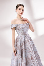 Set against a light backdrop, a woman dons an off - shoulder, light - purple gown with a marble - like pattern. It has short sleeves, a fitted bodice, and a full skirt, along with pockets for practicality. The unique pattern and elegant design make it ideal for formal gatherings, radiating sophistication.5