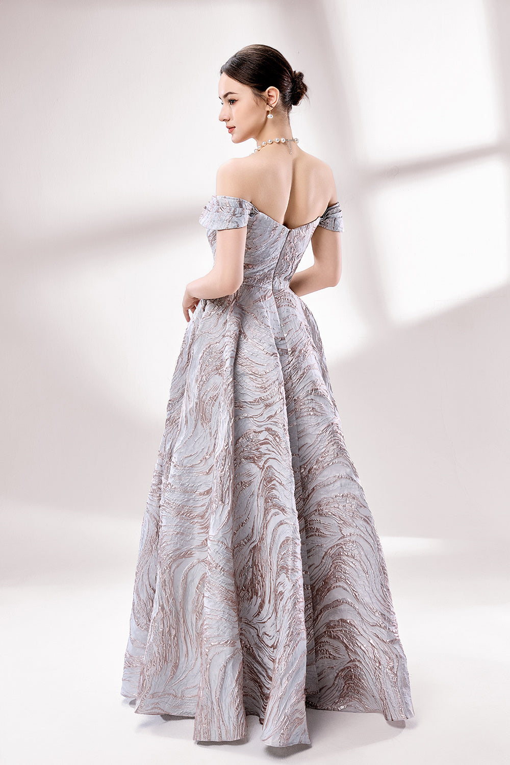 Set against a light backdrop, a woman dons an off - shoulder, light - purple gown with a marble - like pattern. It has short sleeves, a fitted bodice, and a full skirt, along with pockets for practicality. The unique pattern and elegant design make it ideal for formal gatherings, radiating sophistication.2