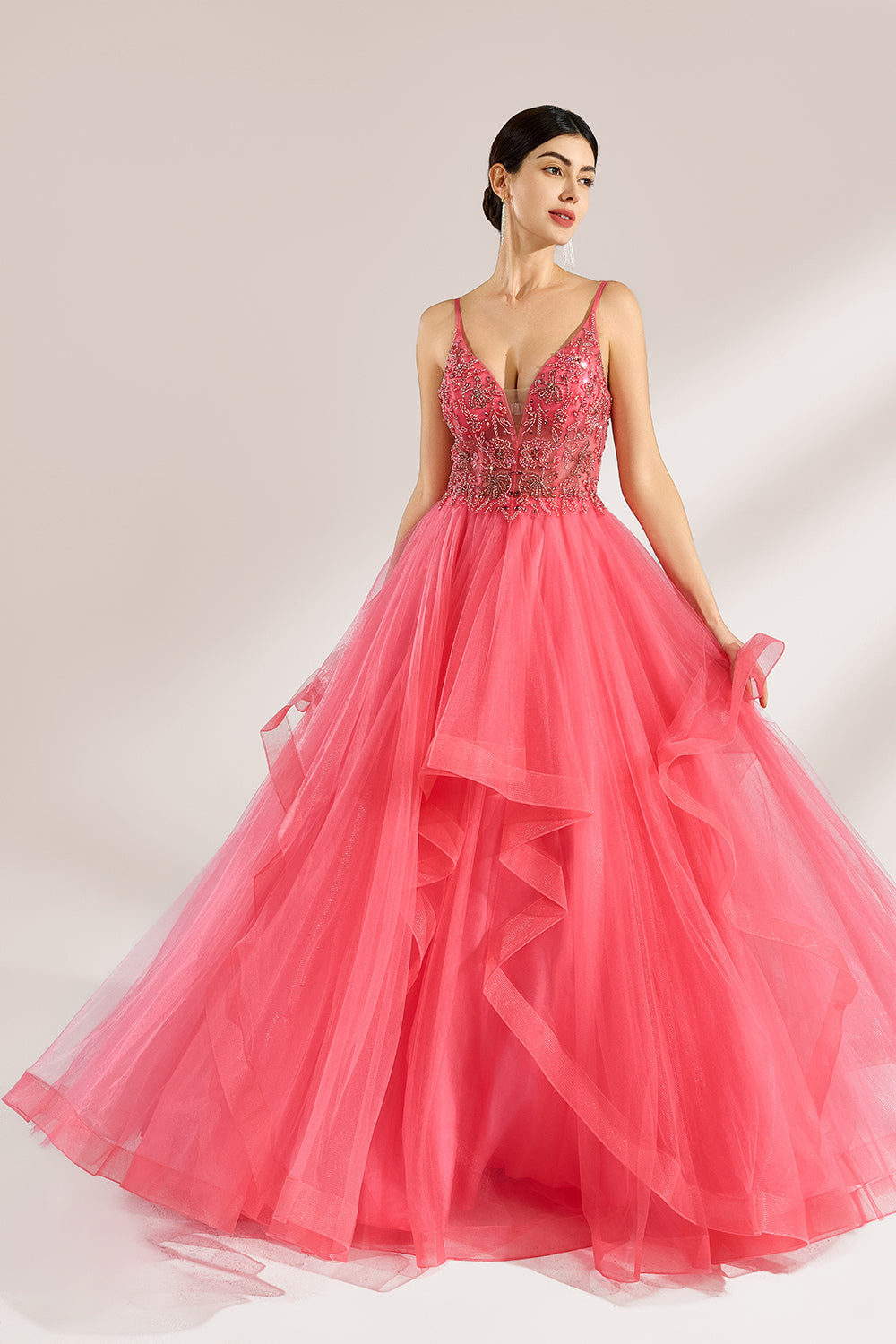 A woman stands against a light background, wearing a coral - pink tulle gown. It features thin straps, a deep V - neckline, and intricate bead embroidery on the bodice. The layered, ruffled tulle skirt creates a romantic and voluminous look, perfect for formal events like proms or weddings.1