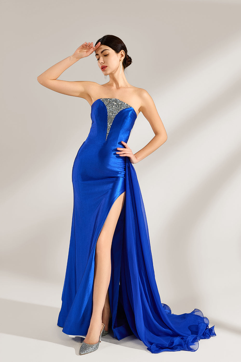 Set against a light background, a woman wears a royal - blue strapless gown. It features a sparkling embellished neckline, a high side slit, and a flowing train. The elegant design creates a glamorous and sophisticated look, perfect for formal events like galas or red - carpet moments.4