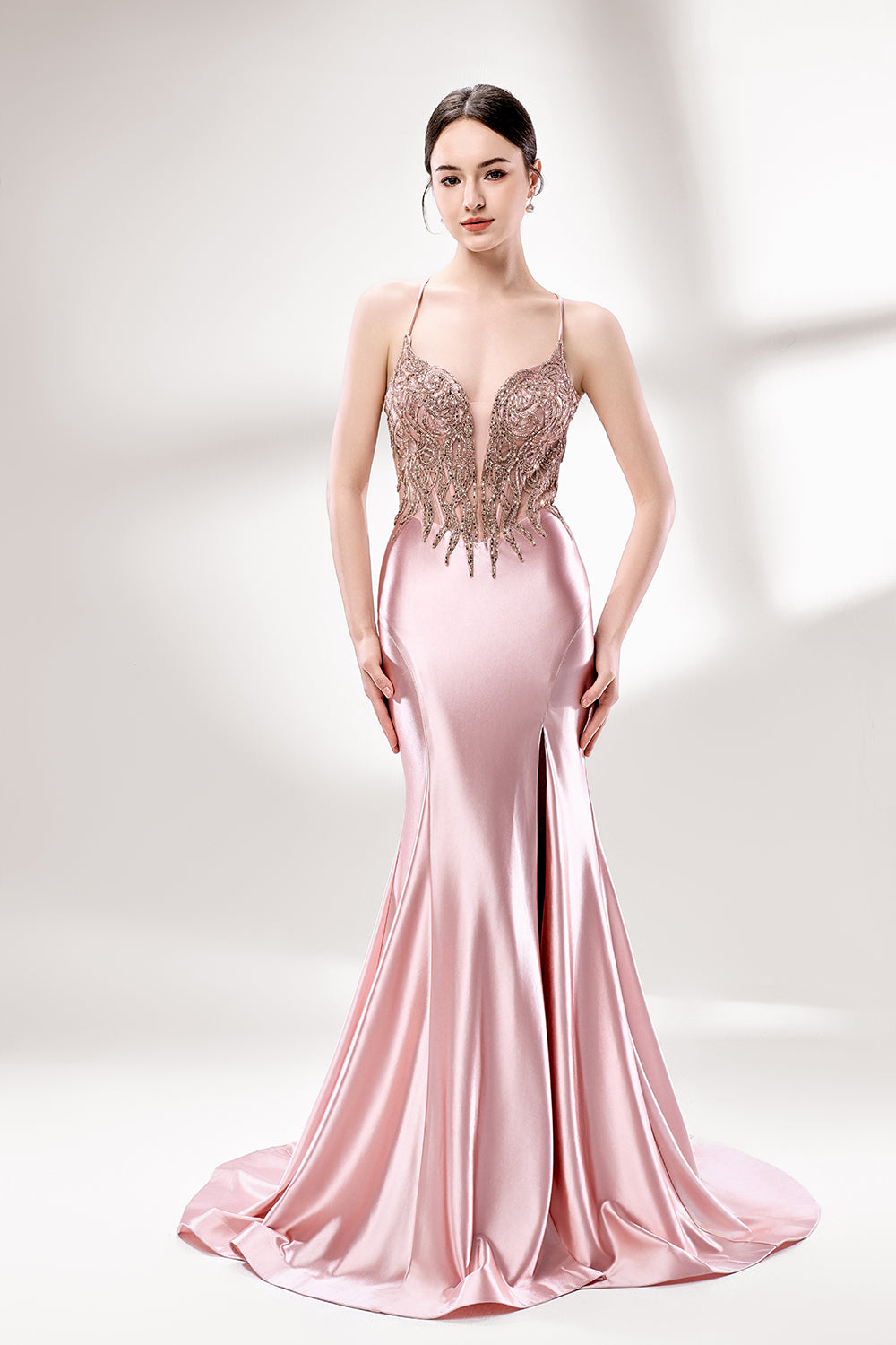 Set against a light backdrop, a woman dons a pink satin gown with a beaded, sheer bodice and a mermaid silhouette. The intricate bead patterns and flowing train add romance, combining sophistication and allure. Ideal for weddings or formal ceremonies, it exudes a regal aura.1