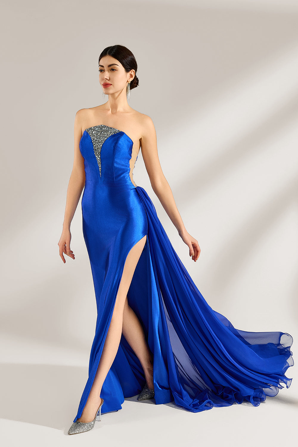 Set against a light background, a woman wears a royal - blue strapless gown. It features a sparkling embellished neckline, a high side slit, and a flowing train. The elegant design creates a glamorous and sophisticated look, perfect for formal events like galas or red - carpet moments.1
