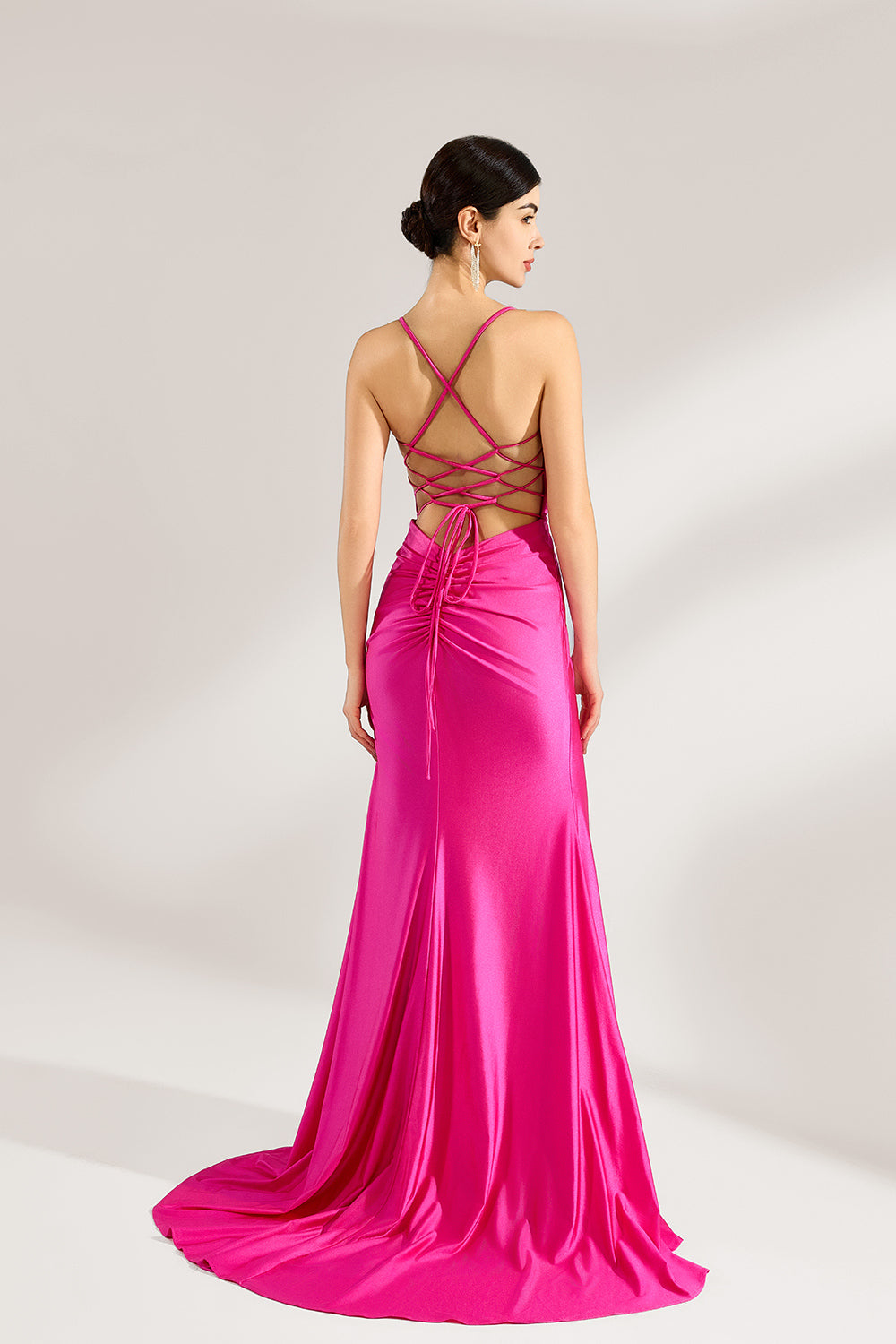 A woman stands against a light background, wearing a hot - pink satin gown. It features thin straps, a deep V - neckline, a draped bodice, a high side slit with crystal embellishments, and a trailing skirt. The elegant design creates a glamorous look, perfect for formal events like galas or red - carpet occasions.2