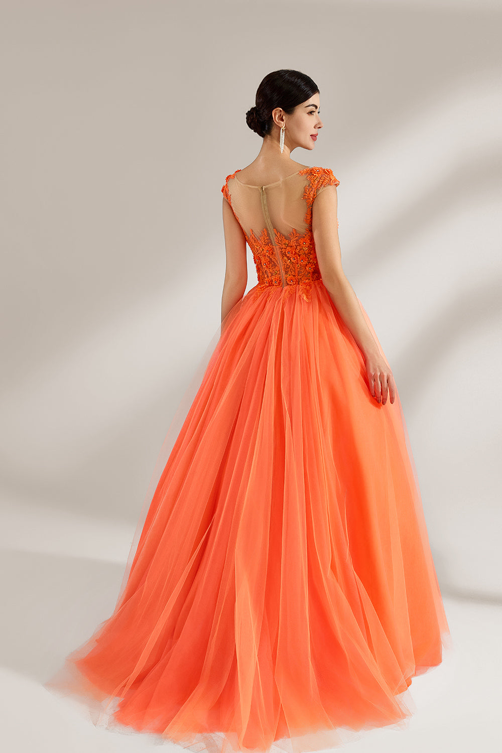 Presented against a light backdrop, a woman dons an orange ball - gown style dress. It features a sheer neckline with delicate floral lace embroidery on the bodice, and a voluminous tulle skirt. The vibrant design creates a lively and elegant look, perfect for formal events like proms or weddings.2