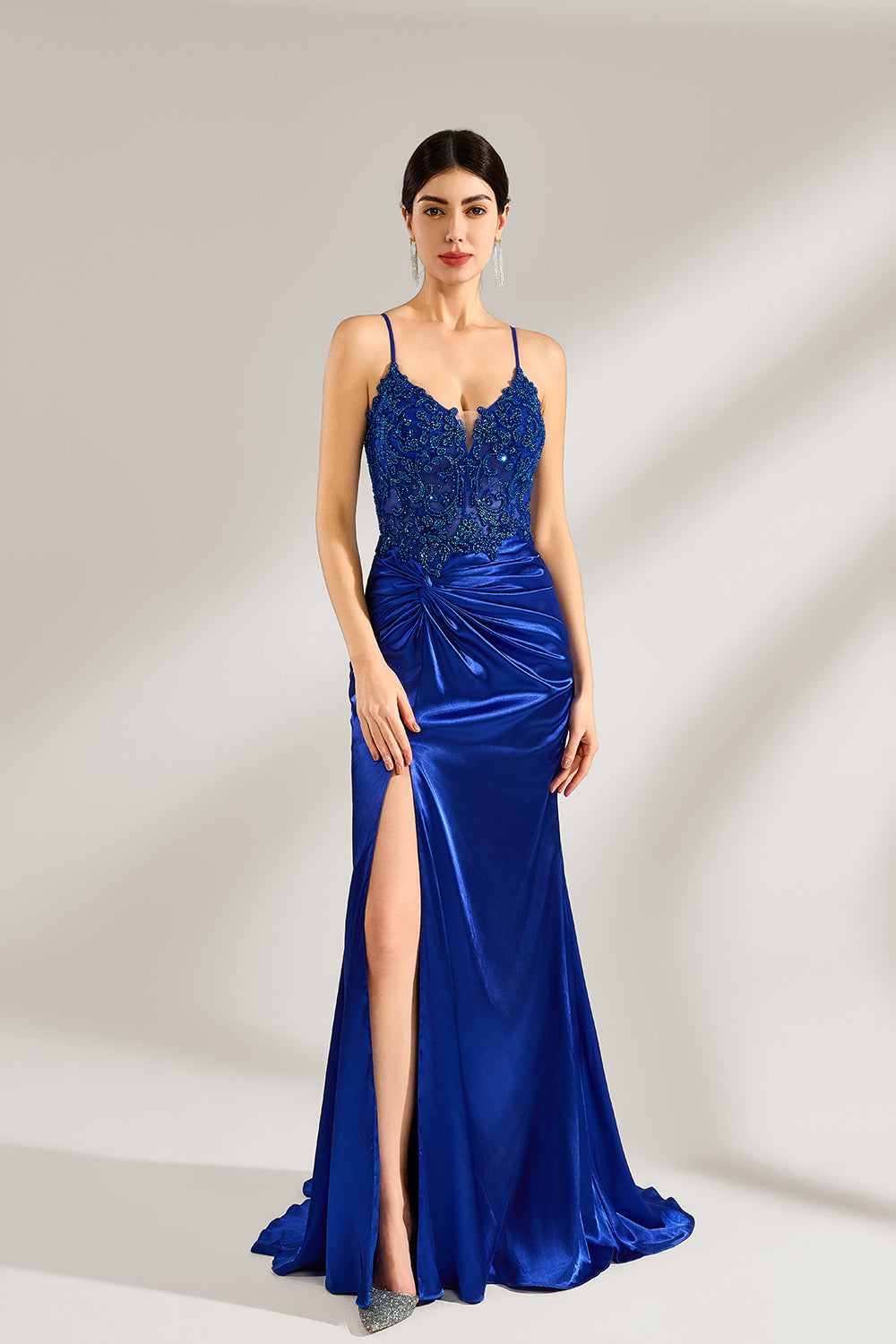 A woman stands against a light background, wearing a royal - blue satin gown. It features thin criss - cross straps at the back, intricate lace embroidery on the bodice, and a mermaid silhouette with a trailing skirt. The elegant design creates a glamorous look, perfect for formal events like galas or red - carpet occasions.1
