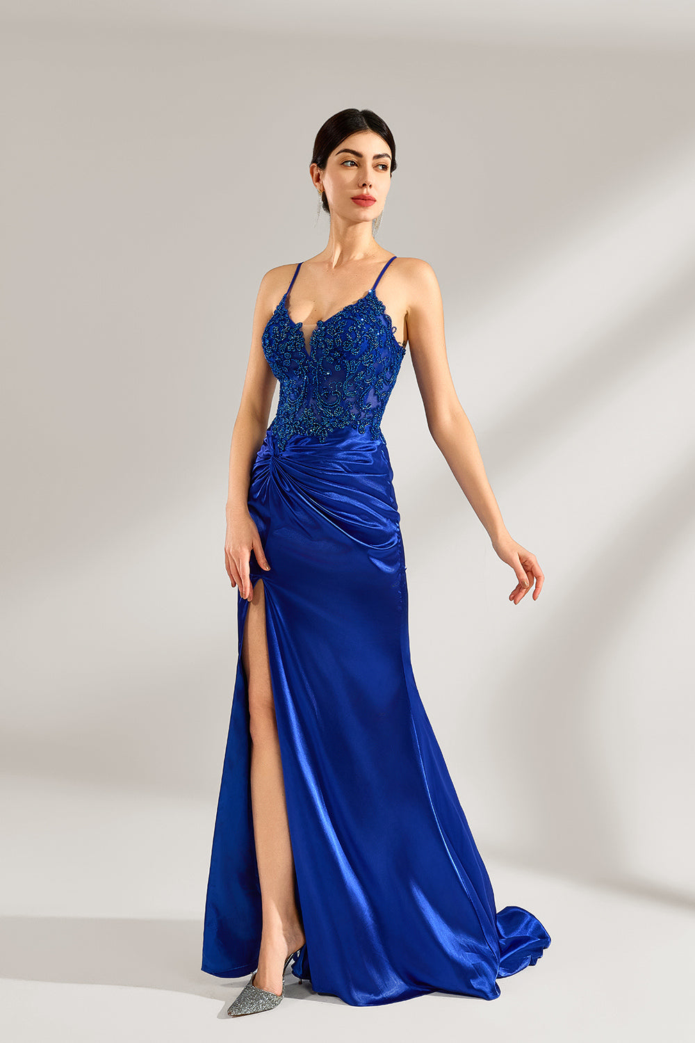 A woman stands against a light background, wearing a royal - blue satin gown. It features thin criss - cross straps at the back, intricate lace embroidery on the bodice, and a mermaid silhouette with a trailing skirt. The elegant design creates a glamorous look, perfect for formal events like galas or red - carpet occasions.3