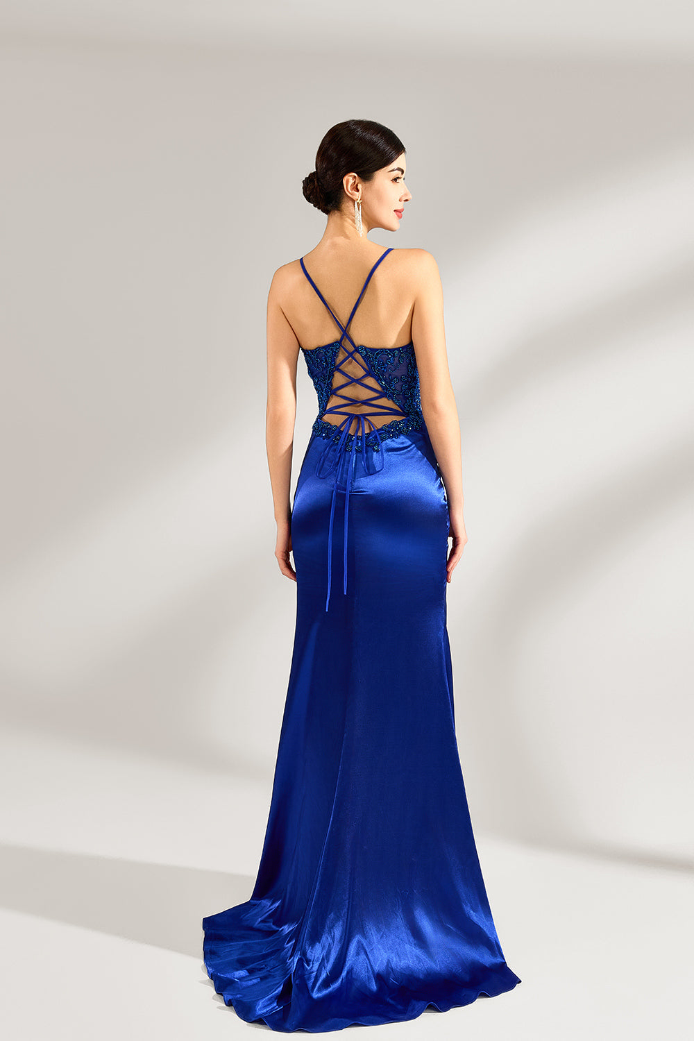 A woman stands against a light background, wearing a royal - blue satin gown. It features thin criss - cross straps at the back, intricate lace embroidery on the bodice, and a mermaid silhouette with a trailing skirt. The elegant design creates a glamorous look, perfect for formal events like galas or red - carpet occasions.
2