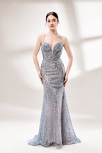 A woman stands against a light - hued background, wearing a light - grey, sheer gown adorned with intricate silver - toned bead patterns. It has thin straps, a deep V - neckline, and a mermaid silhouette. The detailed beadwork and sheer fabric create a glamorous look, perfect for proms or formal parties, radiating sophistication.1