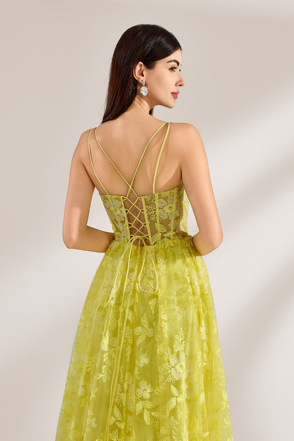 Bathed in soft light, a woman dazzles in a yellow floral - patterned gown. It has thin straps, a fitted bodice, and a high side slit. The flowing skirt creates an elegant and vibrant look, perfect for formal events or special occasions.6
