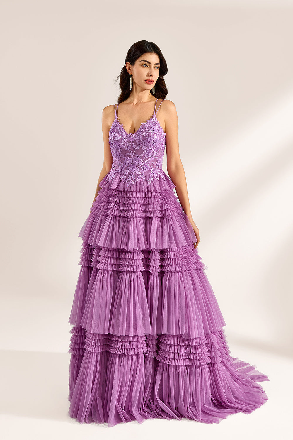 A woman stands against a light background, wearing a lavender tulle gown. It has thin straps, a deep V - neckline, and intricate floral lace embroidery on the bodice. The multi - layered, ruffled tulle skirt with a train creates a romantic and voluminous look, perfect for formal events like weddings or proms, exuding elegance and charm.4