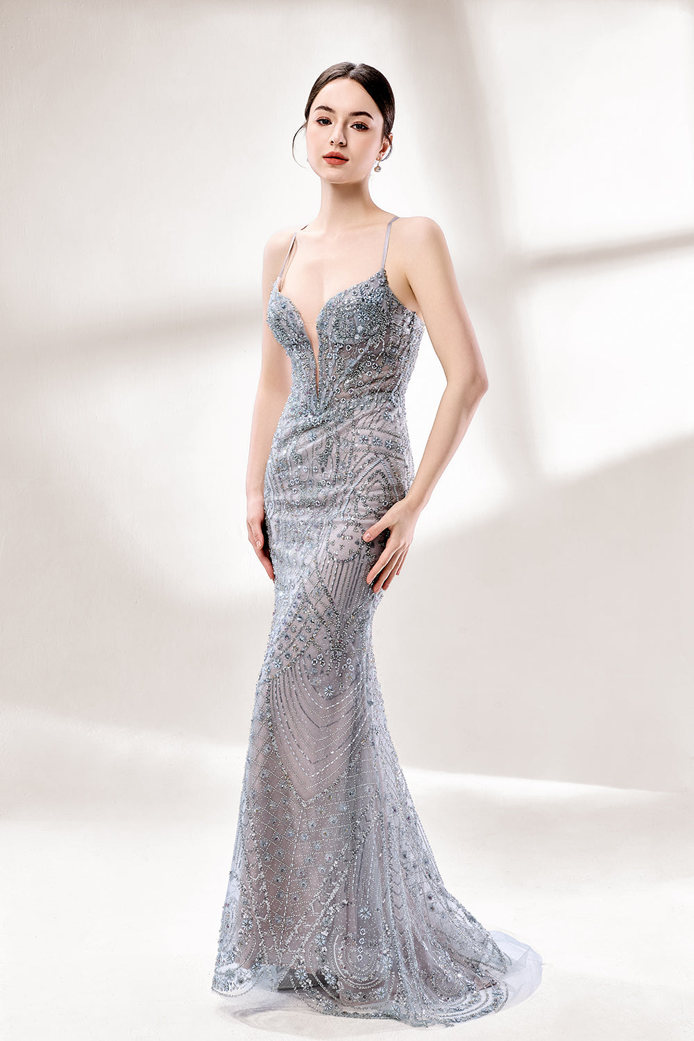 A woman stands against a light - hued background, wearing a light - grey, sheer gown adorned with intricate silver - toned bead patterns. It has thin straps, a deep V - neckline, and a mermaid silhouette. The detailed beadwork and sheer fabric create a glamorous look, perfect for proms or formal parties, radiating sophistication.4