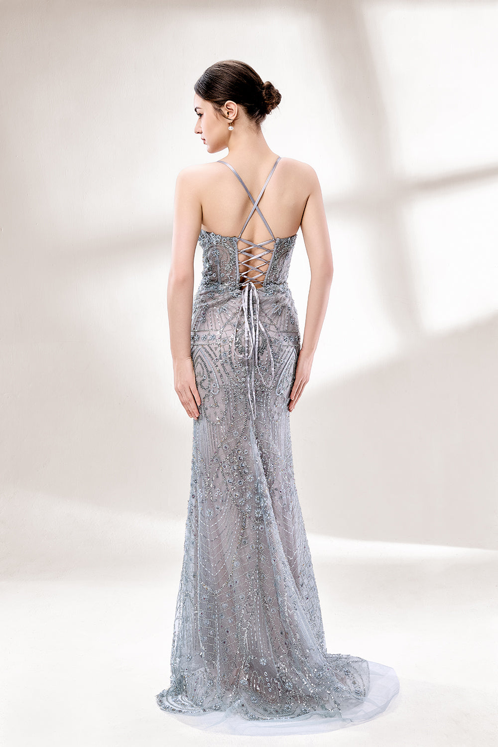 A woman stands against a light - hued background, wearing a light - grey, sheer gown adorned with intricate silver - toned bead patterns. It has thin straps, a deep V - neckline, and a mermaid silhouette. The detailed beadwork and sheer fabric create a glamorous look, perfect for proms or formal parties, radiating sophistication.2