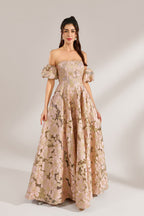 A woman with long, wavy dark hair and a poised stance wears a light - pink, floral - embroidered off - the - shoulder gown. It has puffed sleeves, a fitted bodice, and a voluminous skirt. Paired with understated heels, the outfit radiates elegance, perfect for formal events like galas or weddings.3