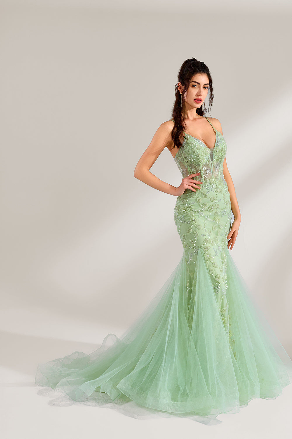 The model wearing it has long, wavy hair tied up in a half-up style, and she accessorizes with elegant earrings. The dress adopts a fresh light green color. The spaghetti strap design reveals the graceful shoulder and neck lines, and the deep V-neck adds a touch of sexiness. The mermaid skirt is paired with light tulle, embellished with exquisite embroidery and beading, making the whole dress look elegant and luxurious. It is very suitable for formal occasions such as dinners and weddings.3