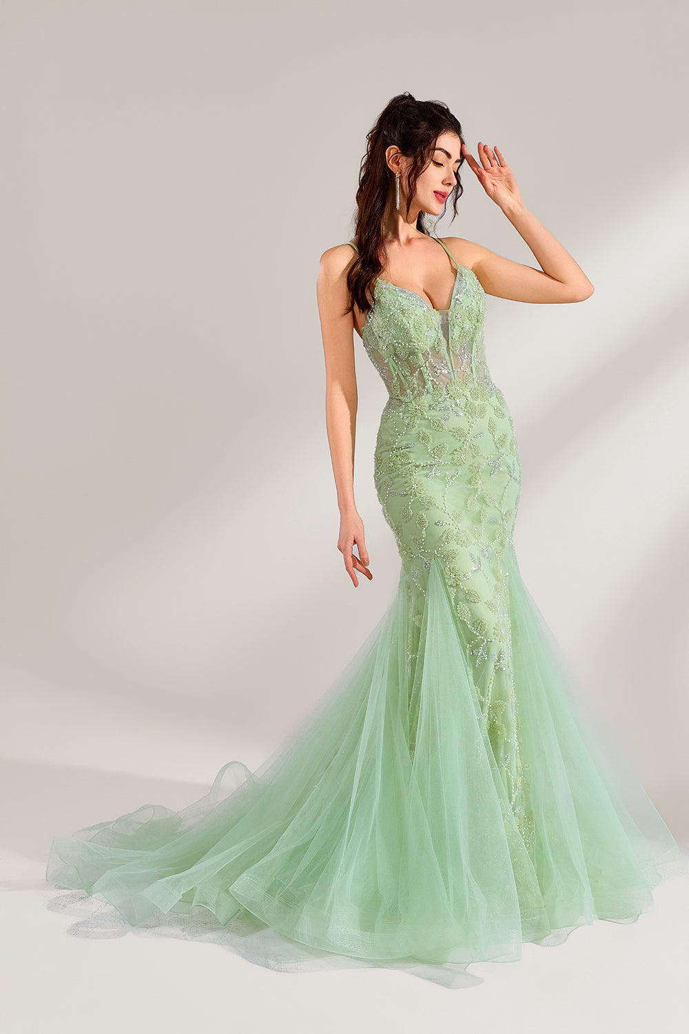 The model wearing it has long, wavy hair tied up in a half-up style, and she accessorizes with elegant earrings. The dress adopts a fresh light green color. The spaghetti strap design reveals the graceful shoulder and neck lines, and the deep V-neck adds a touch of sexiness. The mermaid skirt is paired with light tulle, embellished with exquisite embroidery and beading, making the whole dress look elegant and luxurious. It is very suitable for formal occasions such as dinners and weddings.4