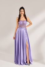 A woman with long, wavy dark hair and a confident pose wears a light - purple satin gown. It has thin straps, a sheer lace - detailed bodice, and a high side slit. Paired with silver - tone heels, the outfit radiates elegance, perfect for formal events like galas or evening receptions.4