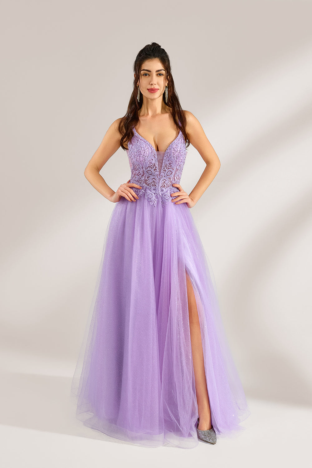Against a light - hued background, a woman adorns a lavender tulle gown. It has thin straps, a deep V - neckline with delicate lace embroidery on the bodice, and a high side slit. The voluminous tulle skirt, shimmering faintly, gives off an elegant and romantic vibe, ideal for formal events such as proms or weddings.3