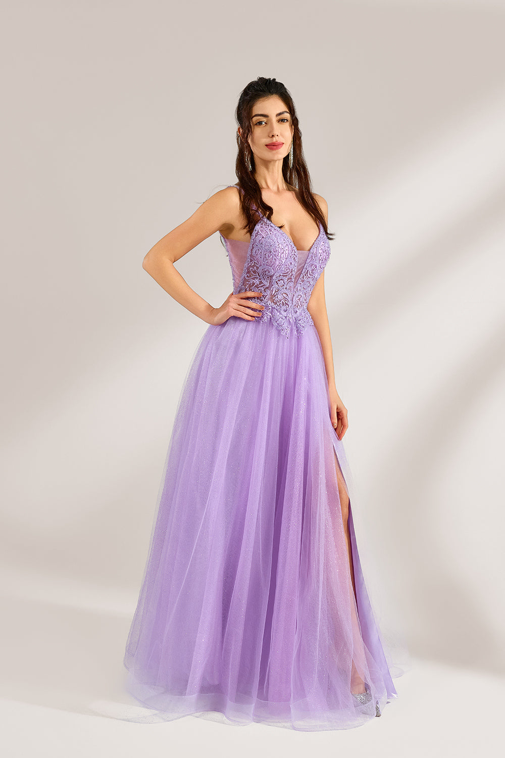 Against a light - hued background, a woman adorns a lavender tulle gown. It has thin straps, a deep V - neckline with delicate lace embroidery on the bodice, and a high side slit. The voluminous tulle skirt, shimmering faintly, gives off an elegant and romantic vibe, ideal for formal events such as proms or weddings.4