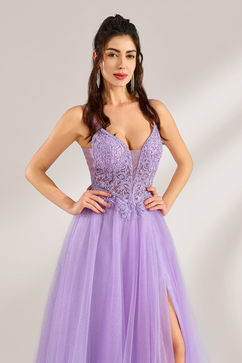 Against a light - hued background, a woman adorns a lavender tulle gown. It has thin straps, a deep V - neckline with delicate lace embroidery on the bodice, and a high side slit. The voluminous tulle skirt, shimmering faintly, gives off an elegant and romantic vibe, ideal for formal events such as proms or weddings.5