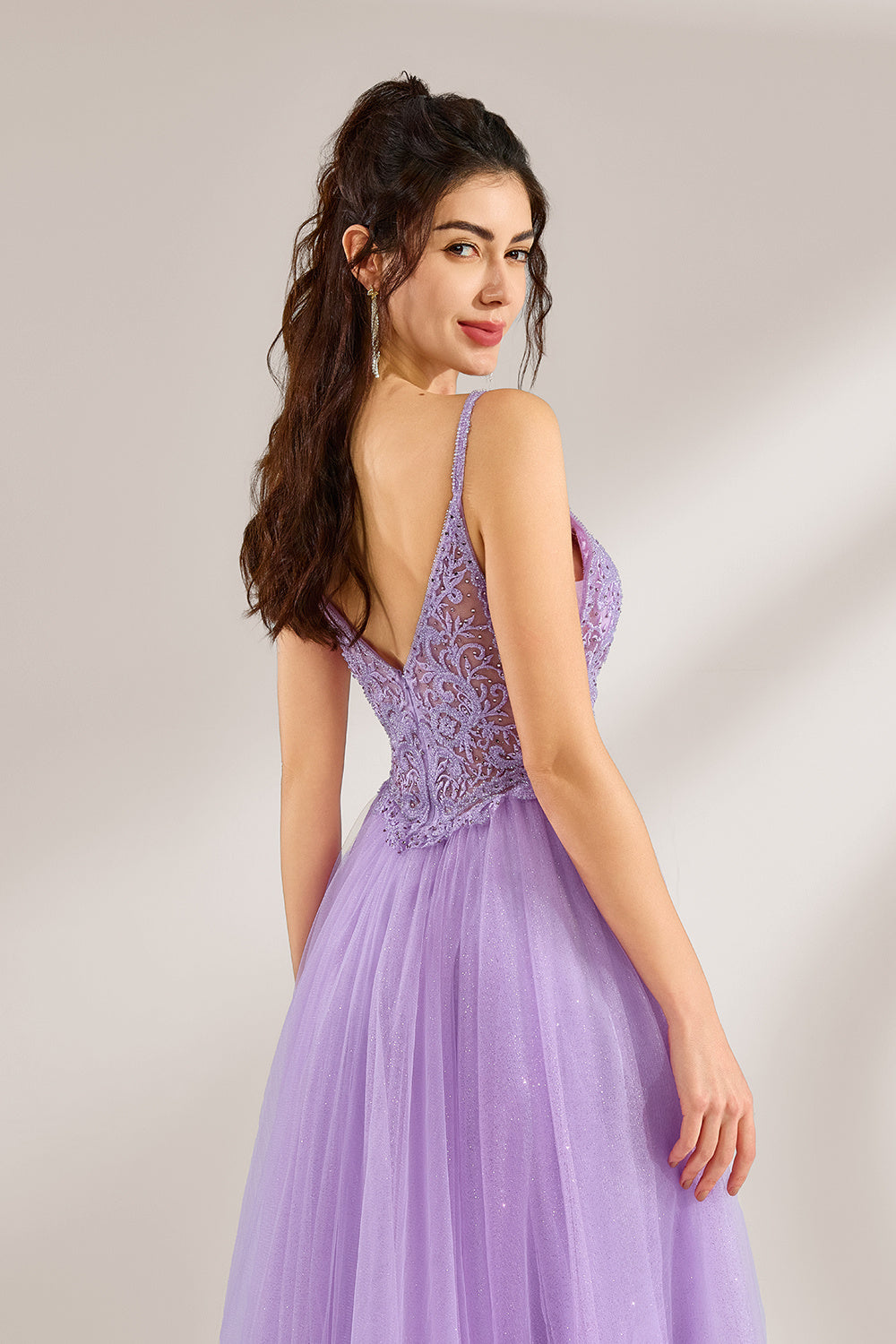 Against a light - hued background, a woman adorns a lavender tulle gown. It has thin straps, a deep V - neckline with delicate lace embroidery on the bodice, and a high side slit. The voluminous tulle skirt, shimmering faintly, gives off an elegant and romantic vibe, ideal for formal events such as proms or weddings.6