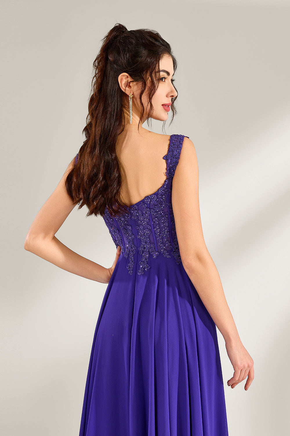 Against a light backdrop, a woman is seen in a purple chiffon gown. It comes with wide straps, a sweetheart neckline, and the bodice is decorated with intricate lace embroidery. There's also a high side slit, and the flowing chiffon skirt gives an elegant and graceful appearance, ideal for formal events such as proms or weddings.5