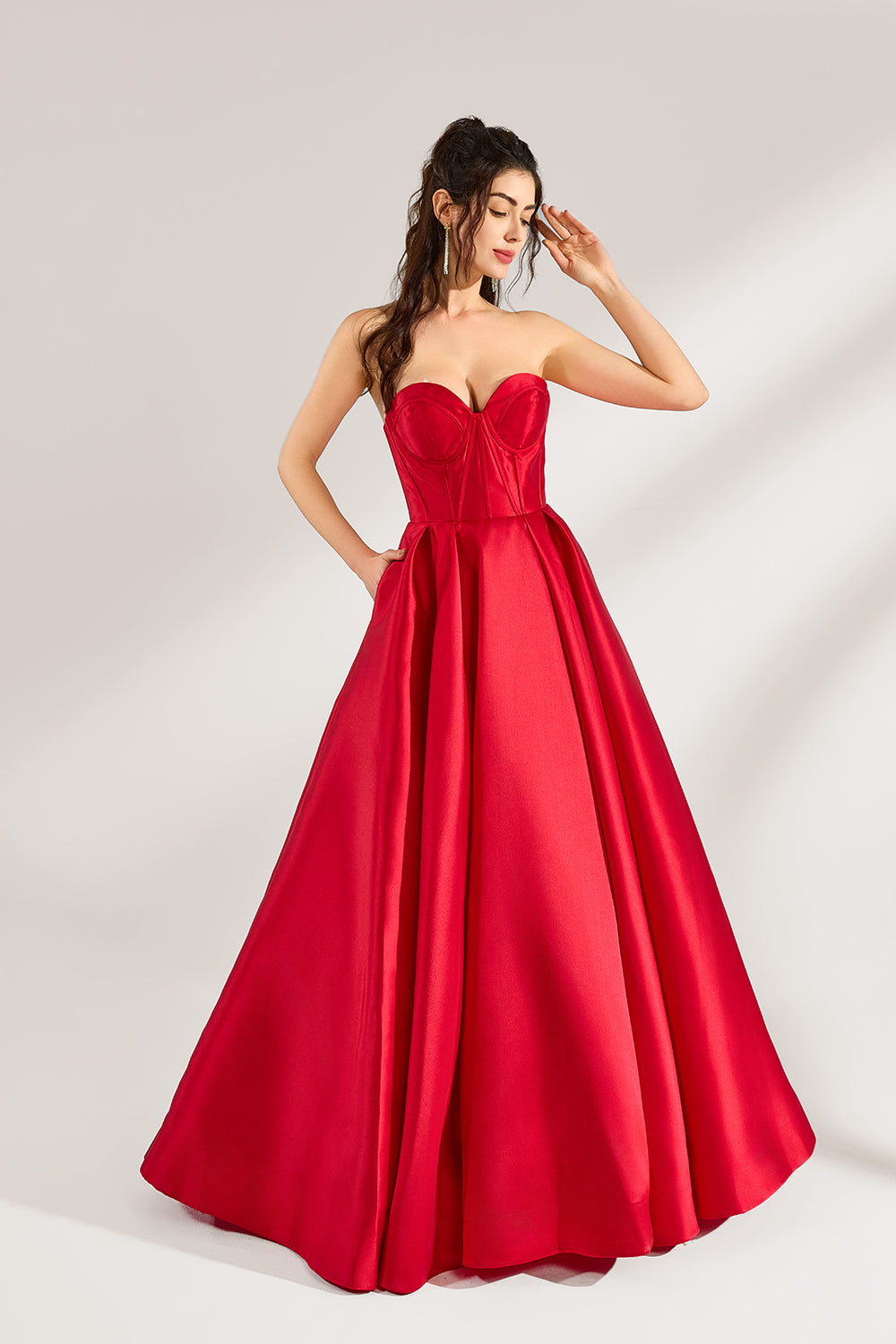 A woman stands against a light background, wearing a red satin strapless ball gown. The sweetheart neckline and voluminous skirt create an elegant and classic look, perfect for formal events like proms or weddings.3
