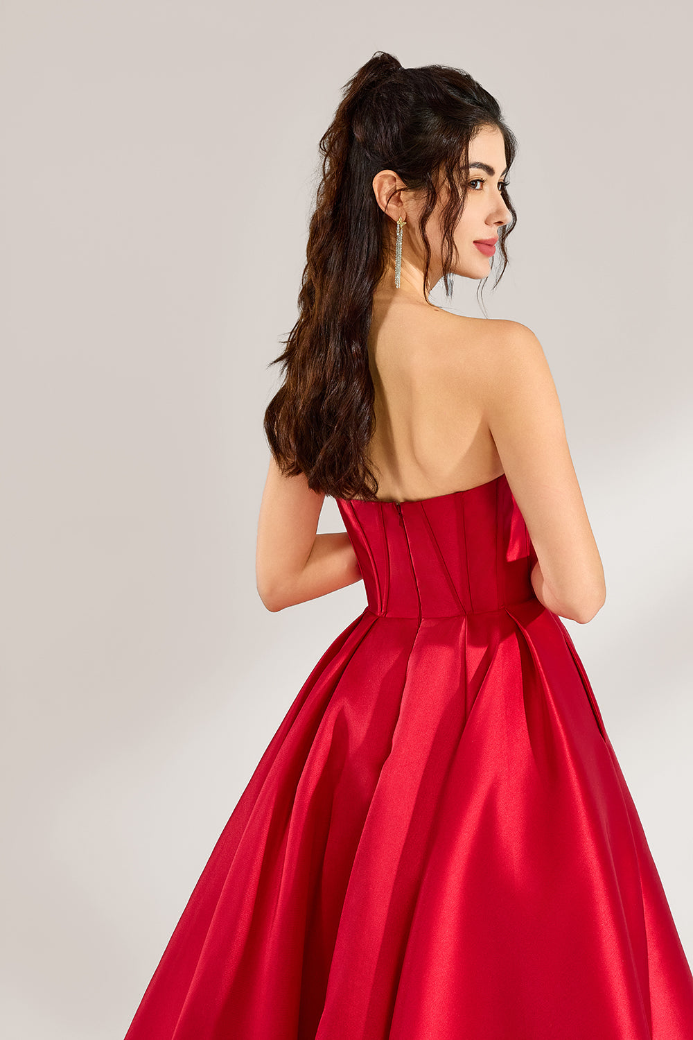 A woman stands against a light background, wearing a red satin strapless ball gown. The sweetheart neckline and voluminous skirt create an elegant and classic look, perfect for formal events like proms or weddings.6