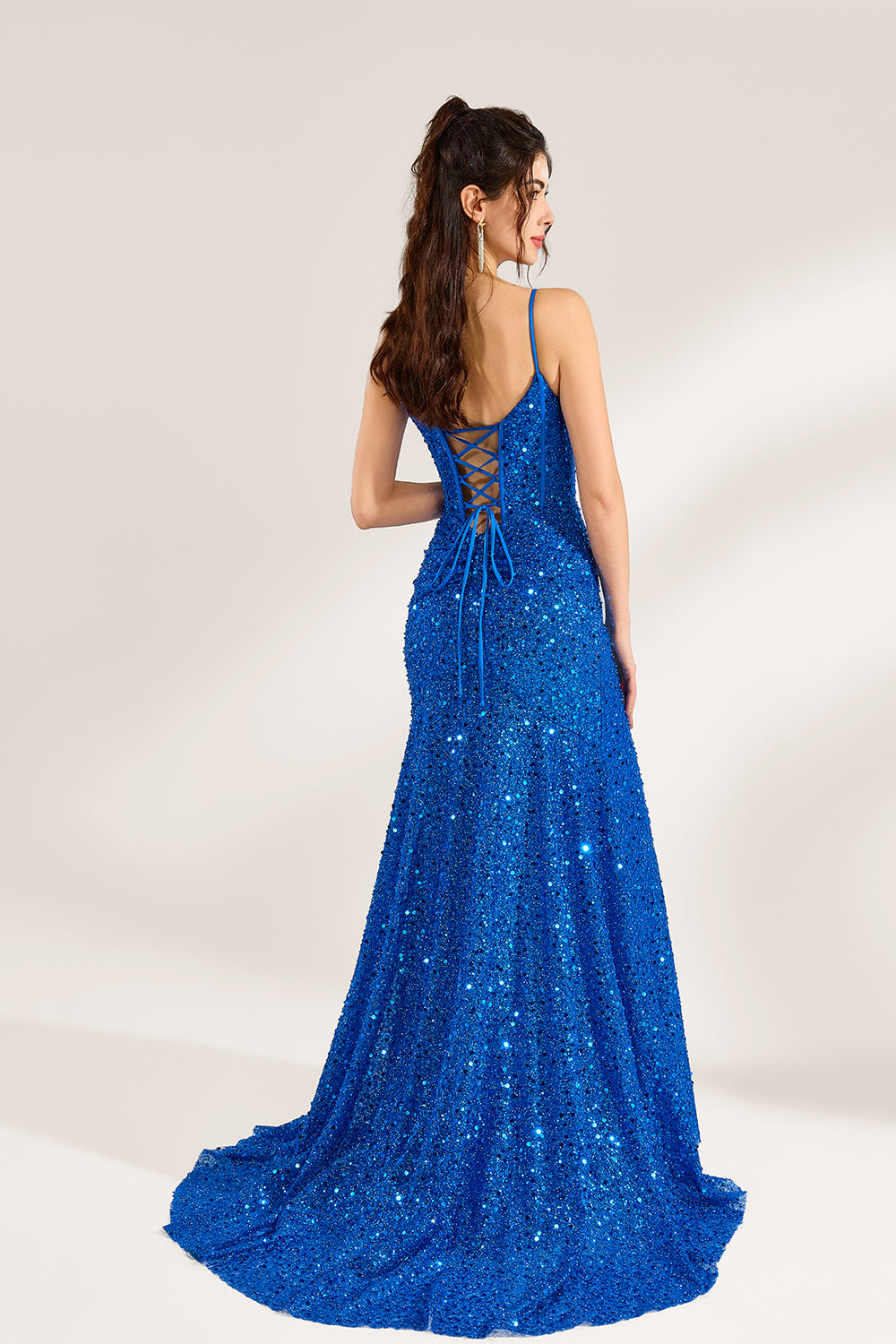 A woman stands against a light background, wearing a royal - blue sequin - covered mermaid gown. It features thin straps, a deep V - neckline with sheer panels, and a high side slit. The sparkling sequins create a glamorous look, perfect for formal events like galas or proms, exuding elegance and charm.3