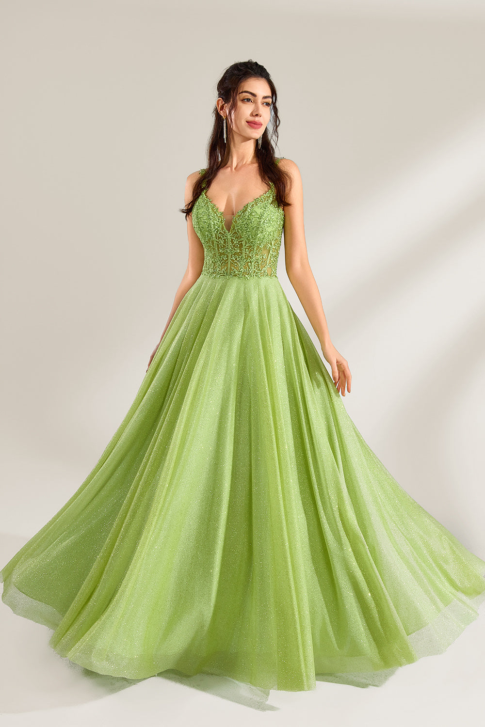 A woman stands against a light background, wearing a lime - green tulle gown. It features thin straps, a deep V - neckline, and intricate lace embroidery on the bodice. The voluminous tulle skirt creates a romantic and elegant look, perfect for formal events like proms or weddings.1