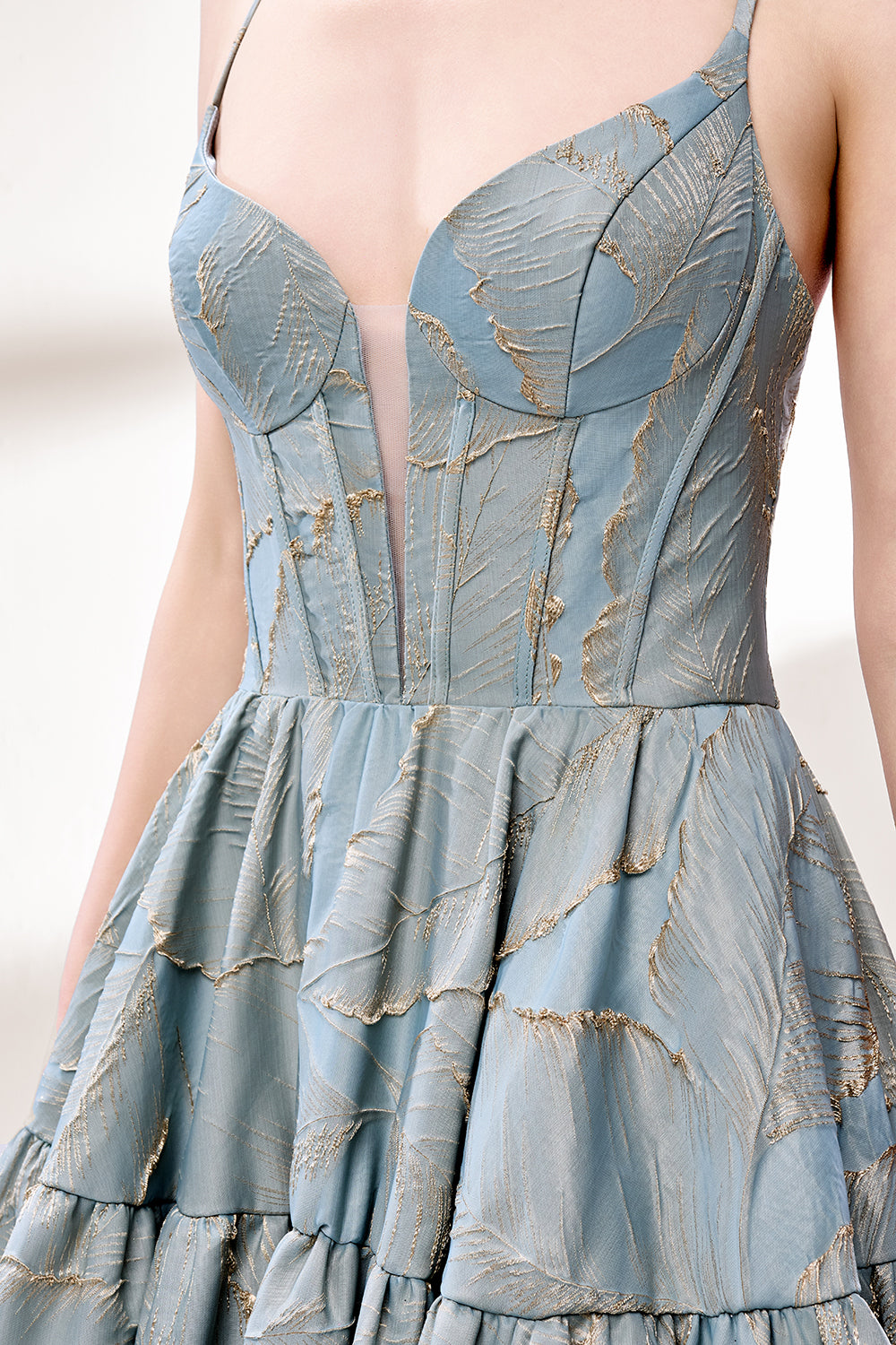 A woman stands against a light background, wearing a light - blue, tiered gown with gold - toned feather patterns. It has thin straps, a deep V - neckline, and a voluminous skirt. The unique jacquard design and elegant silhouette exude romance, perfect for formal events like garden parties or daytime weddings.6