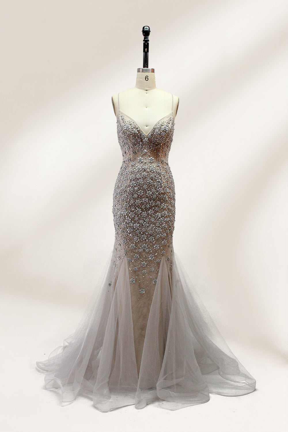 Displayed on a mannequin is a silver - gray mermaid - style gown. It features thin straps, a sweetheart neckline, intricate bead and sequin embroidery throughout, and a flowing tulle skirt. The elegant design creates a glamorous look, perfect for formal events like proms or weddings.1