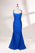 Photograph of a blue, floor-length evening gown displayed on a white dress form. The gown is sleeveless with a fitted bodice and a flared skirt, featuring thin shoulder straps and a textured, ruched design. The dress form is placed against a plain, off-white background, casting soft shadows.01