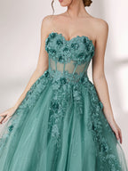 Bathed in soft light, a woman radiates grace in a mint - green evening gown. With floral details, sheer waist, and tulle skirt, it crafts a romantic and elegant look for formal events.6