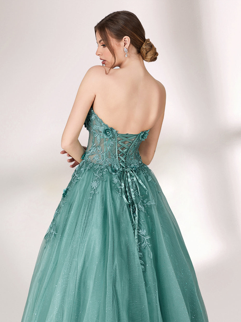 Bathed in soft light, a woman radiates grace in a mint - green evening gown. With floral details, sheer waist, and tulle skirt, it crafts a romantic and elegant look for formal events.4