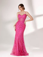 A woman stands against a light background, wearing a bright pink mermaid - style evening gown. It features thin spaghetti straps, a sweetheart neckline, and is covered in shimmering sequins with a sheer, embellished bodice detail. The elegant and glamorous design is perfect for formal events.1