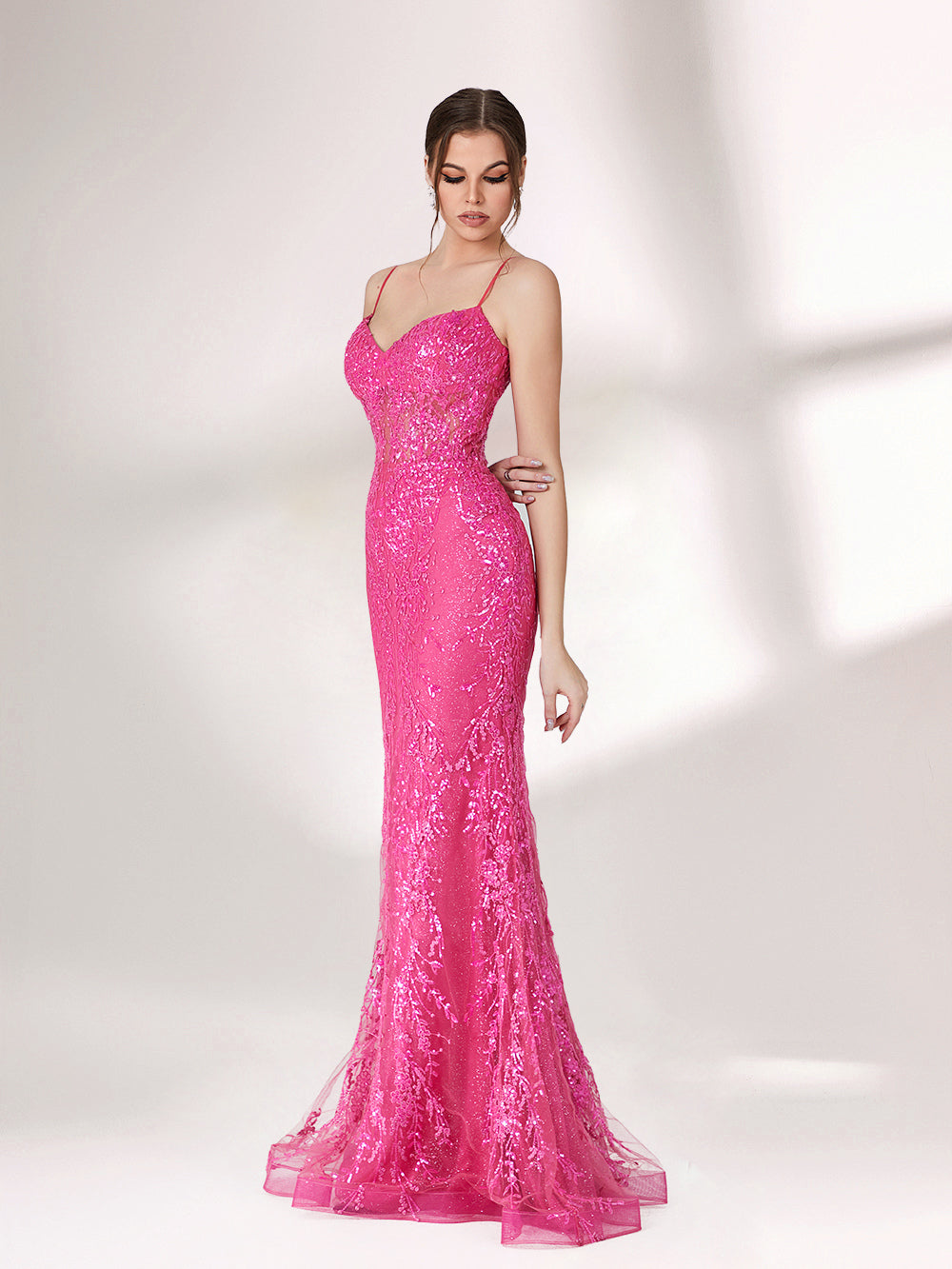 A woman stands against a light background, wearing a bright pink mermaid - style evening gown. It features thin spaghetti straps, a sweetheart neckline, and is covered in shimmering sequins with a sheer, embellished bodice detail. The elegant and glamorous design is perfect for formal events.4