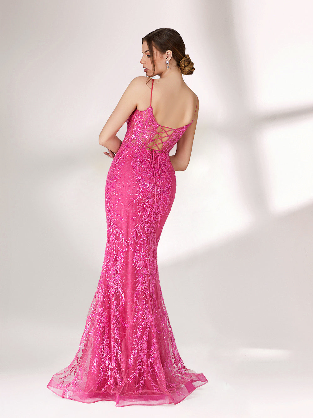 A woman stands against a light background, wearing a bright pink mermaid - style evening gown. It features thin spaghetti straps, a sweetheart neckline, and is covered in shimmering sequins with a sheer, embellished bodice detail. The elegant and glamorous design is perfect for formal events.2