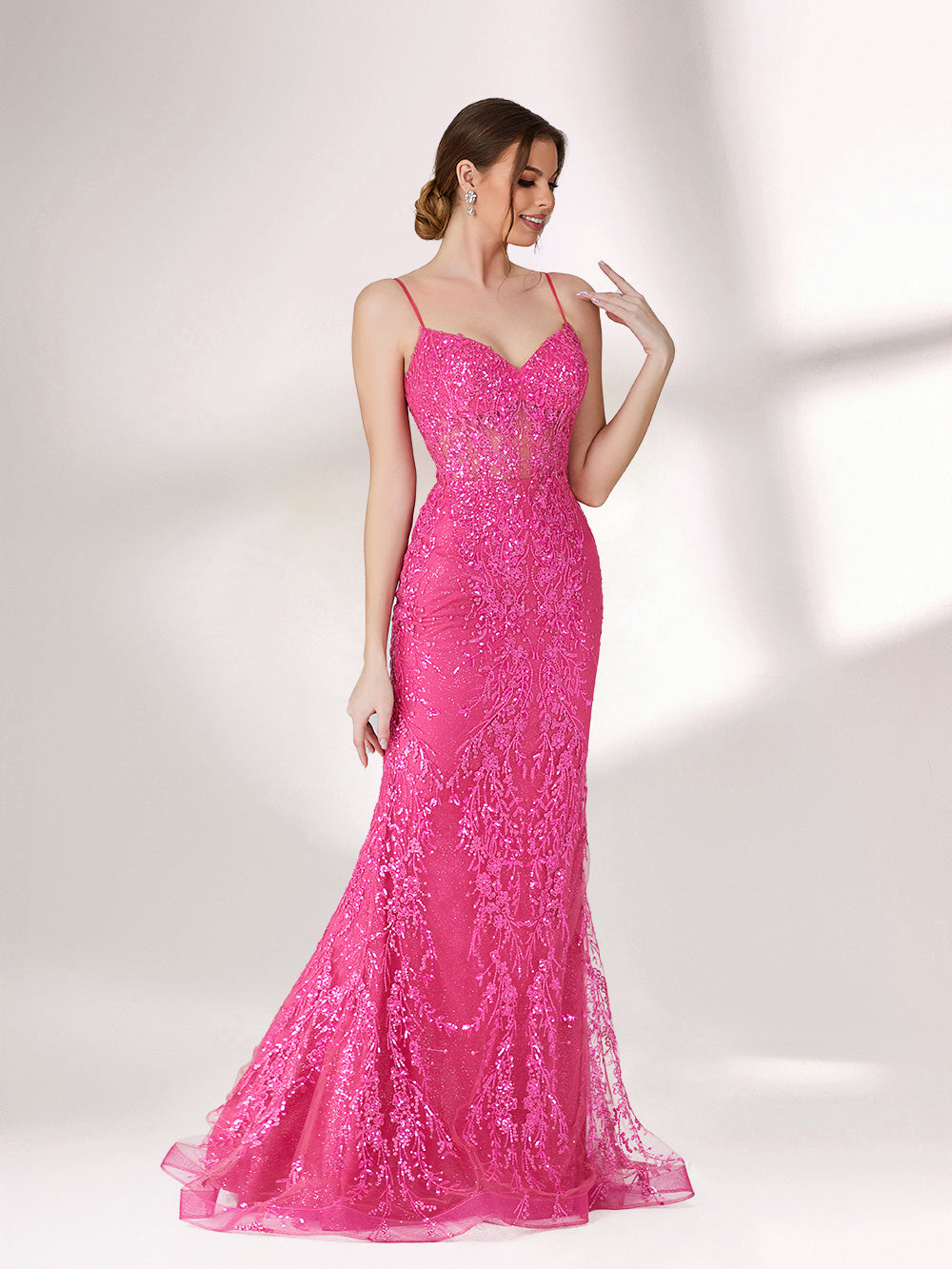 A woman stands against a light background, wearing a bright pink mermaid - style evening gown. It features thin spaghetti straps, a sweetheart neckline, and is covered in shimmering sequins with a sheer, embellished bodice detail. The elegant and glamorous design is perfect for formal events.5